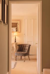 a door leading into a living room with a chair at Casina Cottage in Quenington