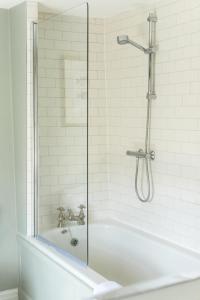 a shower with a glass door next to a tub at Casina Cottage in Quenington