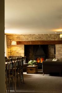 a living room with a fireplace and a table and chairs at Casina Cottage in Quenington