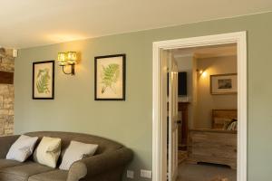 a living room with a couch and pictures on the wall at Casina Cottage in Quenington