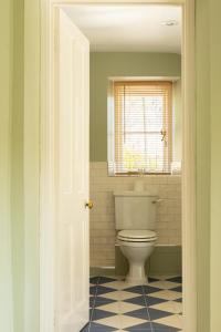 a bathroom with a toilet and a window at Casina Cottage in Quenington