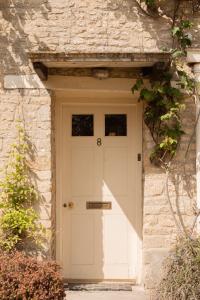 a white front door of a stone house at Casina Cottage in Quenington