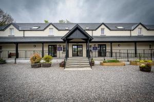 - un grand bâtiment blanc avec une terrasse couverte et des escaliers dans l'établissement Loch Ness Bunk Inn, à Drumnadrochit