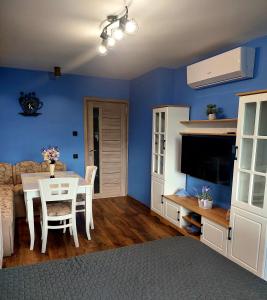 sala de estar con mesa y pared azul en Zara Apartment, en Gorna Oryakhovitsa