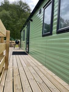 a green building with a deck with a grill on it at Malton 74 in Dunoon