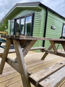 a green tiny house on a wooden deck at Malton 74 in Dunoon
