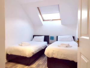 two beds in a small room with a window at Abbey House in Paisley