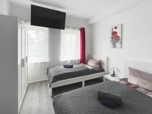 a bedroom with two beds and a tv on the wall at Schwanenburg Apartments in Kolonie Röntgental