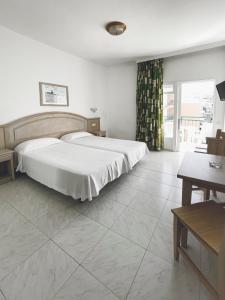 a room with a bed, table, chair and a window at Apartamentos La Carabela in Puerto de la Cruz