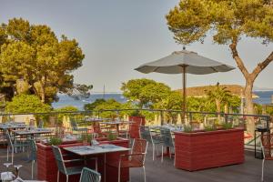 un restaurante con mesas, sillas y sombrilla en Dreams Calvia Mallorca, en Magaluf