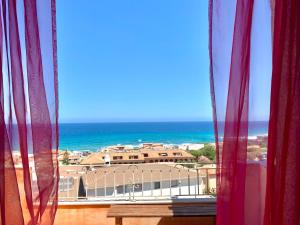 a view of the ocean from a window with red curtains at Residence Lu Bagnu in Castelsardo