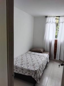 Cama pequeña en habitación con ventana en Apartamento Amoblado Conjunto Terraverde en Ibagué