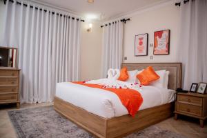 1 dormitorio con 1 cama grande con almohadas de color naranja y blanco en Lux Suites Eldoret Luxury Villas, en Eldoret