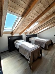 two beds in a room with a large window at Il B&B di Piazza Motta in Albese Con Cassano