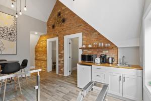 uma cozinha com armários brancos e uma parede de tijolos em ENTIRE 3-UNITS TOP-FLOOR ACROSS FROM GOOGLE em Kitchener