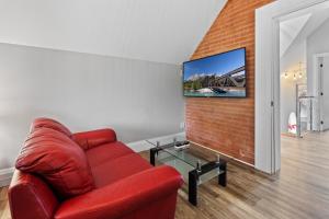 a red couch in a living room with a tv on a brick wall at ENTIRE 3-UNITS TOP-FLOOR ACROSS FROM GOOGLE in Kitchener