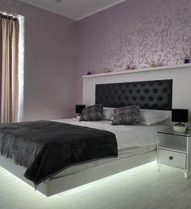 a bedroom with a large bed with a black headboard at Black Sea Vi Dari Apartments in Batumi