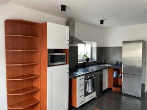 una cocina con electrodomésticos blancos y estanterías de madera en Apartmán Věra, en Pardubice