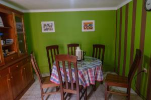 un comedor con una mesa con sillas y paredes verdes en la casa de la guajira, en Cusco