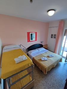 1 dormitorio con 2 camas y ventana en Hotel Primavera sul mare, en Lido di Savio