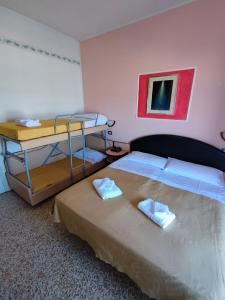 Hotel Primavera sul mare في ليدو دي سافيو: غرفة نوم مع سرير مع سريرين بطابقين
