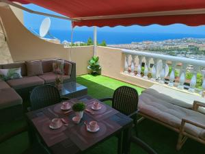 sala de estar con mesa y sillas y balcón en Balcon Atlantico Holiday Tenerife en Adeje
