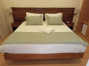 a bed with a wooden headboard and two pillows at Fontanário House in Alpiarça