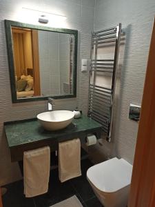 a bathroom with a sink and a toilet and a mirror at Fontanário House in Alpiarça