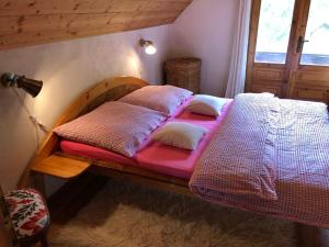 a bed with pink sheets and pillows in a room at Čičmanský ľudový dom in Čičmany