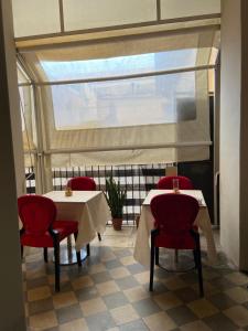 卡塔尼亞的住宿－DS Apartments，餐厅设有两张桌子、红色椅子和窗户