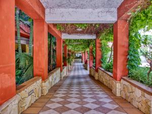 a walkway in a building with red columns and plants at Hotel Caesar Palace in Giardini Naxos