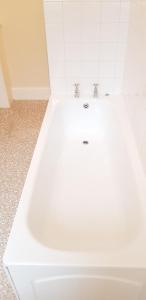 La salle de bains est pourvue d'une baignoire blanche et d'un lavabo. dans l'établissement Banyan tree, à Buxton
