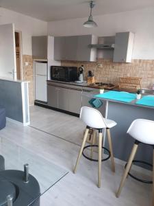 a kitchen with white chairs and a blue counter top at appartement malo les bains plage in Dunkerque