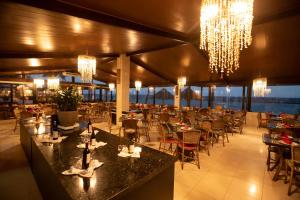 um restaurante com mesas, cadeiras e lustres em Village Barra Hotel em Barra de São Miguel