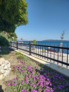 a fence with purple flowers next to the beach at Apartman ll smještaj između Splita i Trogira su Kaštela Dalmacija Hrvatska in Kaštela