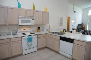 a kitchen with white appliances and wooden cabinets at Grosvenor Villa TM148 in Davenport