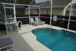 a swimming pool with chairs and a table next to a house at Grosvenor Villa TM148 in Davenport