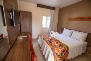 a hotel room with a bed and a flat screen tv at Village Barra Hotel in Barra de São Miguel