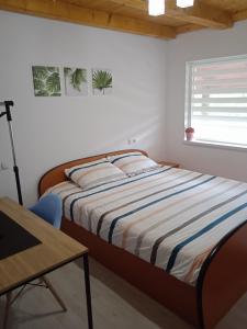Schlafzimmer mit einem Bett, einem Tisch und einem Fenster in der Unterkunft Vila Sabo- Casa de vacanta cu lac de pescuit si ciubar cu hidromasaj in Sîntioana