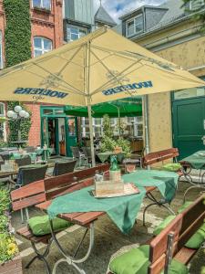 un patio con sombrilla, mesas y sillas en Altwernigeröder Apparthotel en Wernigerode