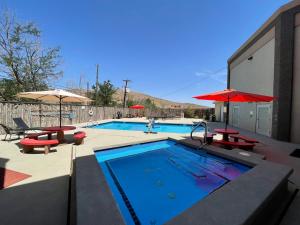 a swimming pool with tables and umbrellas next to a building at Quality Inn Alpine in Alpine