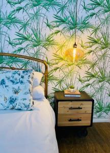 um quarto com uma cama com uma mesa de cabeceira e uma parede com plantas em Mdumela Stays 2 Bedroom Modern City Apartment em Pietermaritzburg