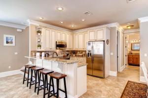 a kitchen with white cabinets and bar stools at House of Kings in Destin