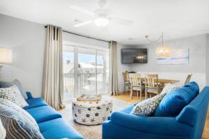 a living room with blue couches and a dining room at Beachside Villas 732- Southbound Serenity in Santa Rosa Beach