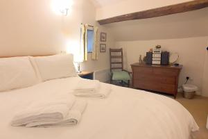 a bedroom with a bed with white sheets and a dresser at Stanton Cottage, Youlgrave Nr Bakewell in Bakewell