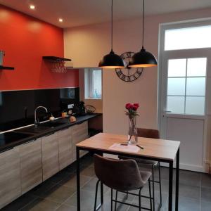 a kitchen with a table with a vase of roses on it at La Demeure d'Ana - Hébergement insolite in Voncq