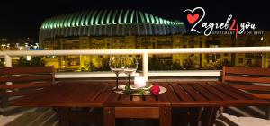 una mesa de madera con copas de vino y una vela en el balcón en Zagreb4you Apartments, en Zagreb