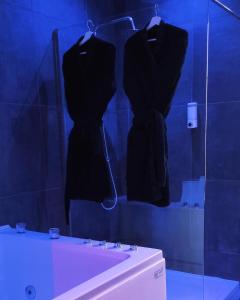 two black dresses hanging on a wall in a bathroom at La Demeure d'Ana - Hébergement insolite in Voncq