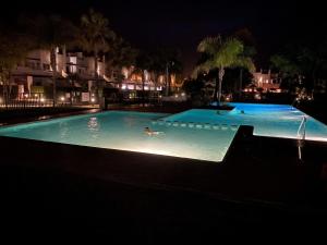 a person swimming in a swimming pool at night at Appartement N618 avec solarium sur golf resort in Alhama de Murcia