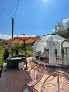 eine Terrasse mit 2 Stühlen, einem Sonnenschirm und einer Badewanne in der Unterkunft Cupola glamping dome Sarajevo in Sarajevo